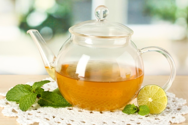 Teapot with mint and lime on table in room