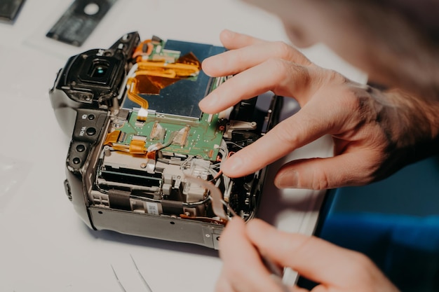 Technician engineer repairs broken photo camera with special tool Photographer busy with maintenance Selective focus Technology repair