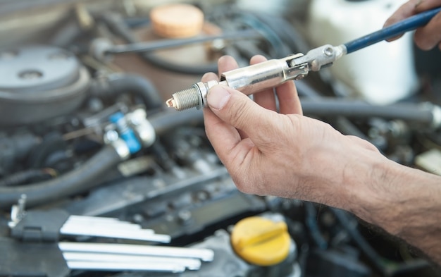 Technician installing new candle in car engine.