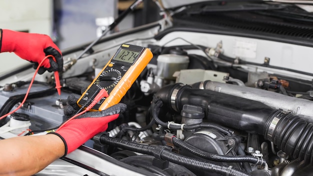 A technician is checking the car battery for availability