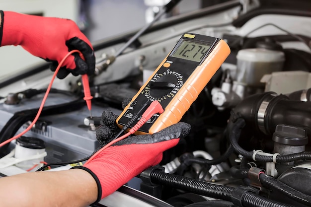 A technician is checking the car battery for availability