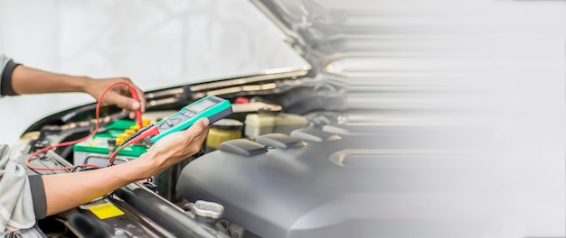 A technician is checking the car battery for availability