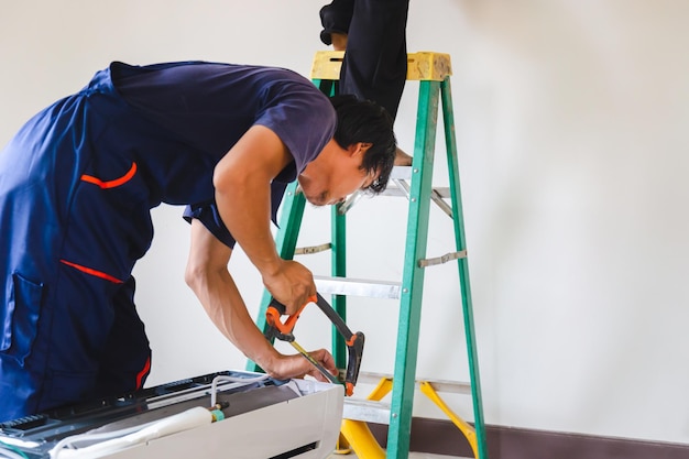 Technician man installing air conditioning in a client house Young repairman fixing air conditioner unit Maintenance and repairing concepts