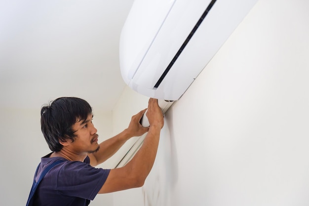 Technician man installing air conditioning in a client house Young repairman fixing air conditioner unit Maintenance and repairing concepts