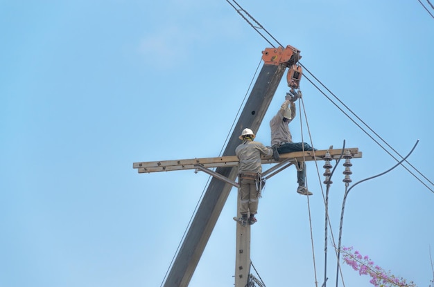 Technician men fixing or repairing broken power line on electric pole highly dangerous work