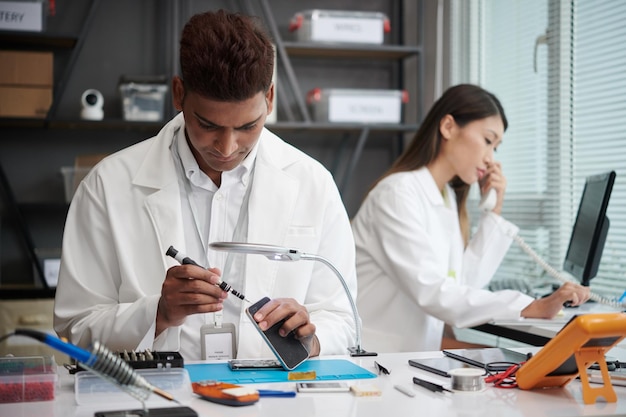 Technician reassembling smartphone when manager talking on phone with client