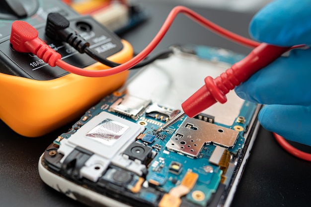 Technician repairing inside of mobile phone by soldering iron. Integrated Circuit. the concept of data, hardware, technology.