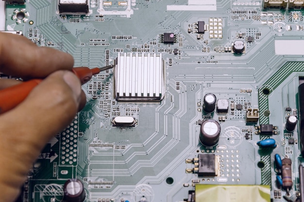 Technician repairing television board ,engineer measures the voltage on the television board