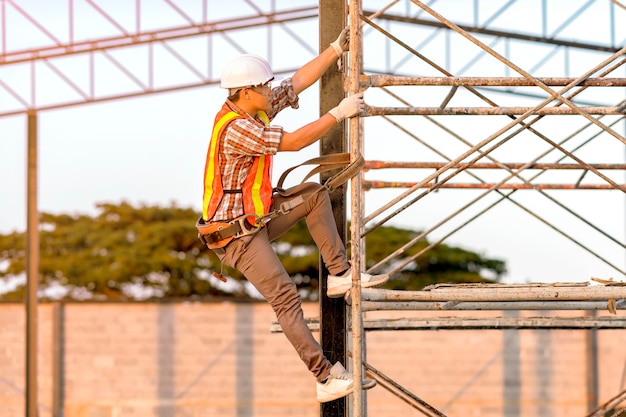 Technician in safety clothing is climbing scaffolding