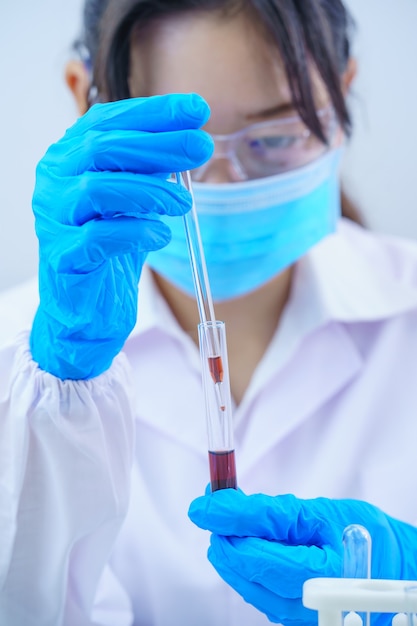 Technician scientist analyzing a blood sample in test tube in laboratory for testing it on COVID, COVID-19, coronavirus virus analysis