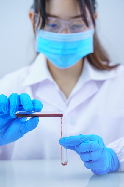 Technician scientist analyzing a blood sample in test tube in laboratory for testing
