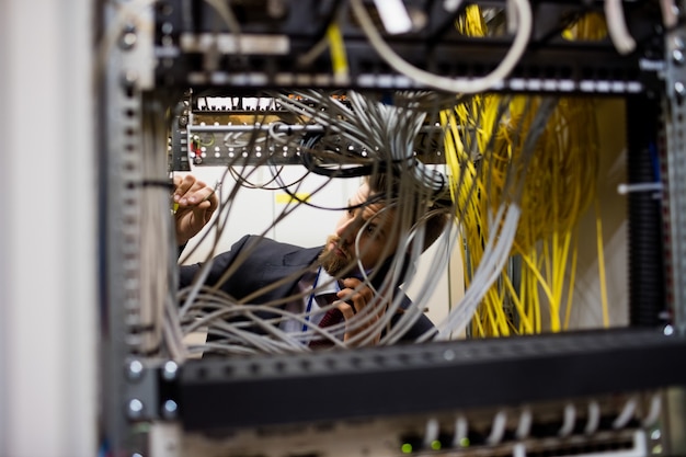 Technician talking on mobile phone while checking cables