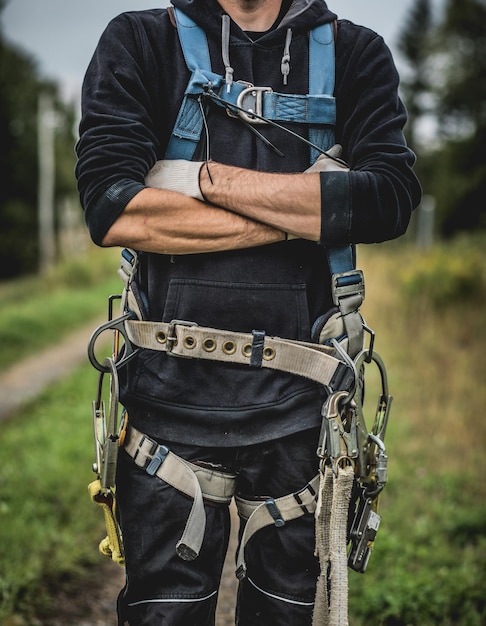 Technician in uniform with harness standing with arms crossed