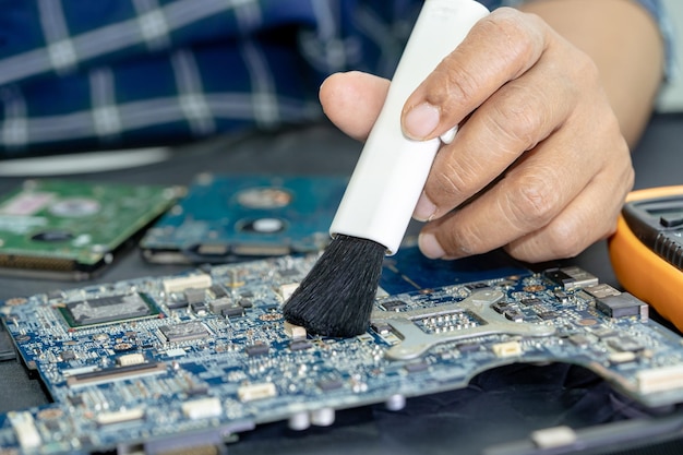 Technician use brush and air blower ball to clean dust in circuit board computer Repair upgrade and maintenance technology