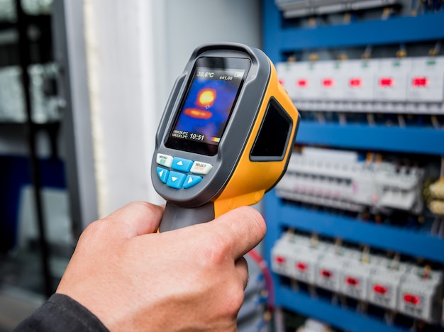 Technician use infrared thermal imaging camera to check temperature at fuse-box