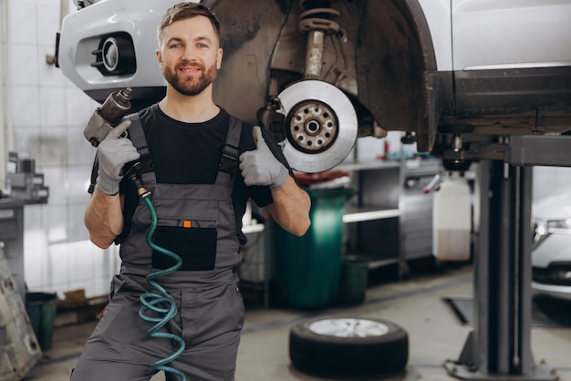 Technician work car service Auto mechanic portrait Guy fix big wheel tire workshop