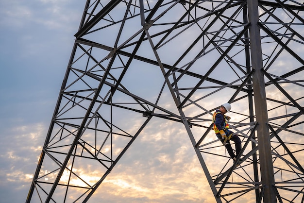 A technician or worker are using safety harnesses to climb highvoltage pylons for inspection and maintenance at highvoltage pylon stations