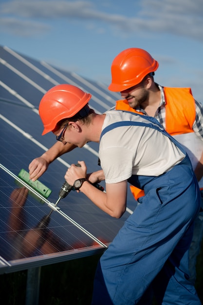 Technicians installing photovoltaic panels at solar power station.