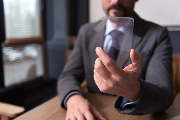 Technological advances. Selective focus of a sophisticated modern smartphone being in hands of a confident successful handsome businessman