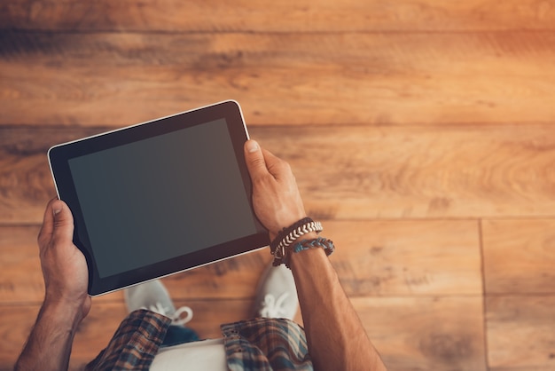 Technologies for better life. Top view of man holding digital tablet while standing on the wooden floor