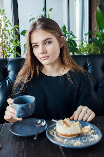 Technologies emotions lifestyle people teens concept Young happy female reading on her mobile phone while sitting in modern coffee shop interior girl with beautiful smile drink tea