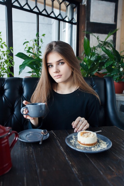 Technologies emotions lifestyle people teens concept Young happy female reading on her mobile phone while sitting in modern coffee shop interior gorgeous hipster girl with beautiful smile