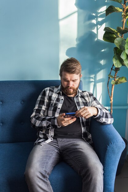 Technologies and leisure concept - Handsome man using smartphone at home.