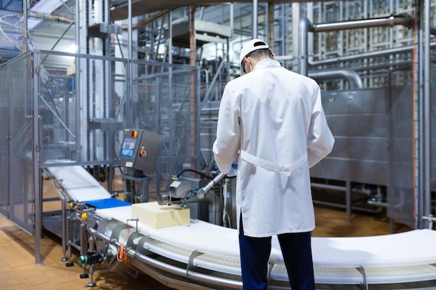 Technologist make set up of the production line while standing near digital screen at the department of dairy factory