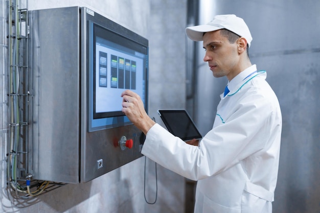 Technologist make set up of the production line while standing near digital screen at the department of dairy factory