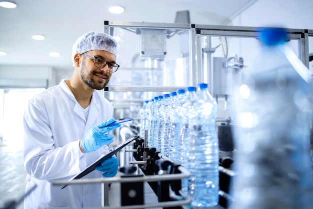 Technologist working in bottling factory doing quality control of drinking water before distribution