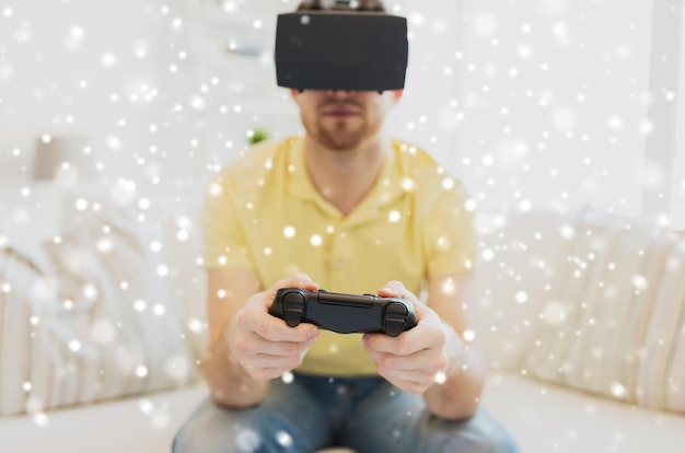 Photo technology, augmented reality, gaming, entertainment and people concept - close up of happy young man with virtual headset or 3d glasses playing video game with controller gamepad at home over snow