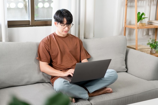 Technology Concept The male who is wearing casual clothes sitting on the sofa and doing his work