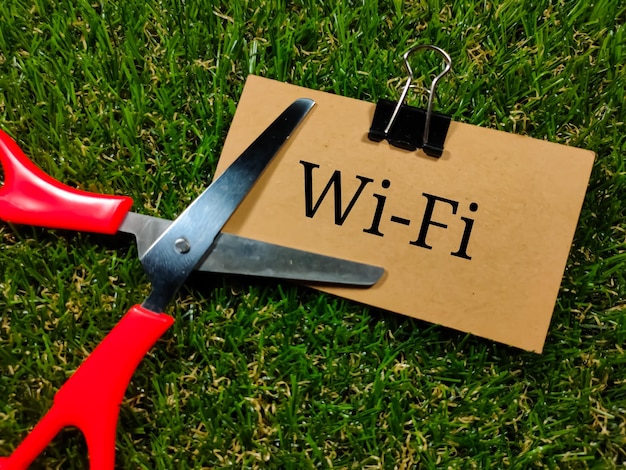 Technology conceptText WIFI writing on brown card with scissors on grass background