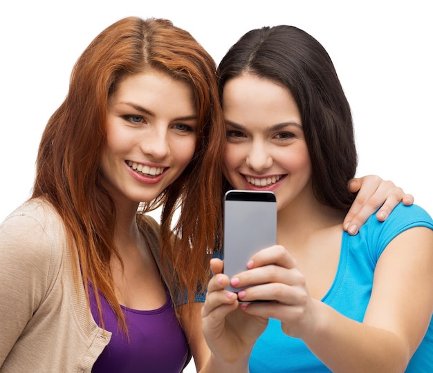 technology, friendship and people concept - two smiling teenagers with smartphone