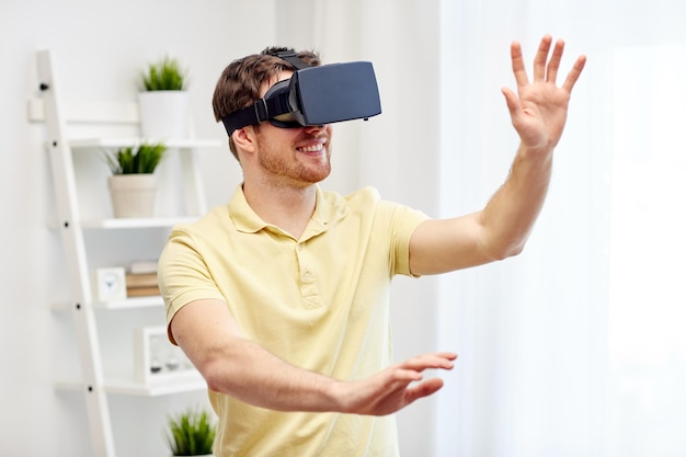 technology, gaming, entertainment and people concept - happy young man with virtual reality headset or 3d glasses playing video game