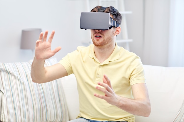 technology, gaming, entertainment and people concept - happy young man with virtual reality headset or 3d glasses playing video game