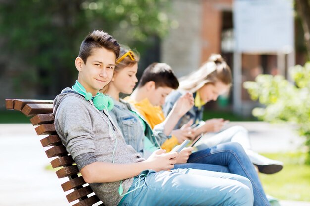 technology, internet and people concept - happy teenage boy with tablet pc computer and headphones outdoors