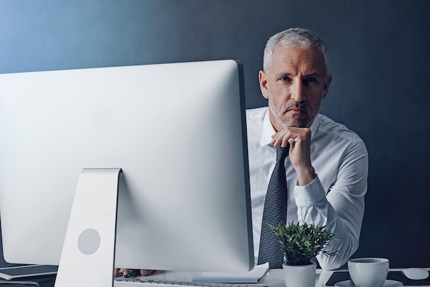 Technology mature man working on his computer and against a studio background Connectivity or social networking browsing internet or website and accountant research at desktop in backdrop