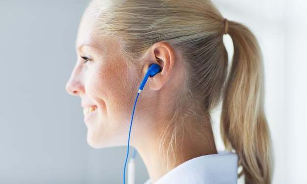 technology, music and people concept - close up of happy smiling woman in earphones at home