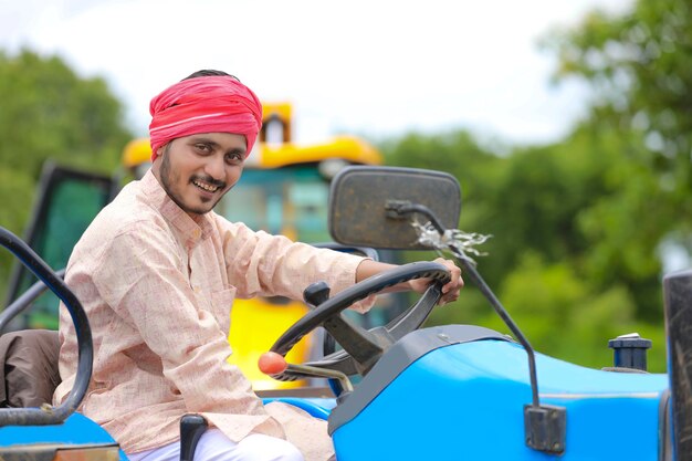 Technology and people concept, Portrait of young indian farmer with tractor