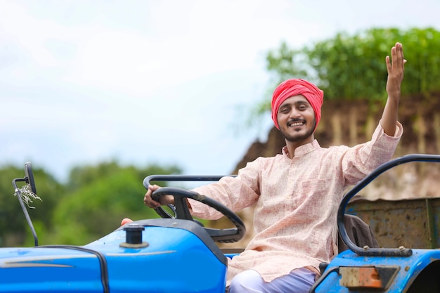 Technology and people concept, Portrait of young indian farmer with tractor