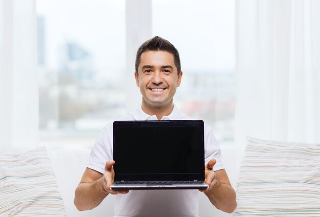 technology, people lifestyle and networking concept - happy man showing laptop black blank screen at home