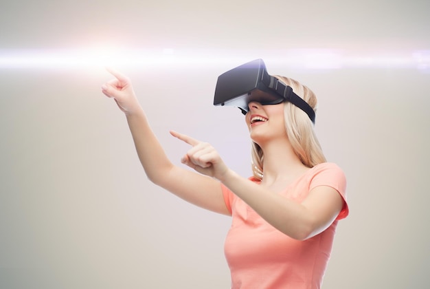 technology, virtual reality, entertainment and people concept - happy young woman with virtual reality headset or 3d glasses over gray background and laser light