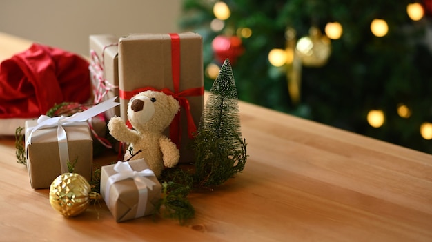 Teddy bear and Christmas presents on wooden table in living room.