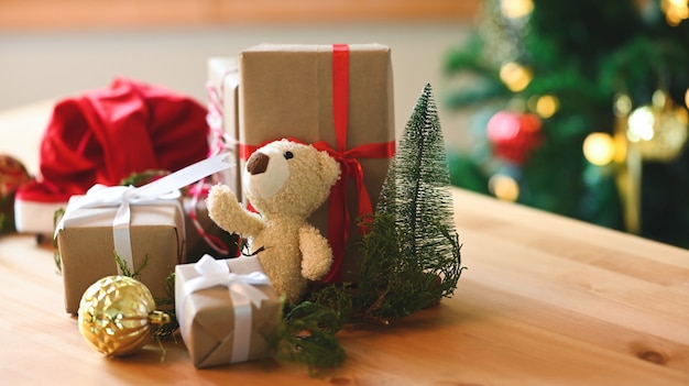 Teddy bear and Christmas presents on wooden table.