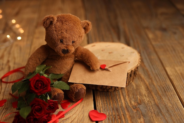 A teddy bear holds a letter and red roses on a wooden background Picture for Valentines Day