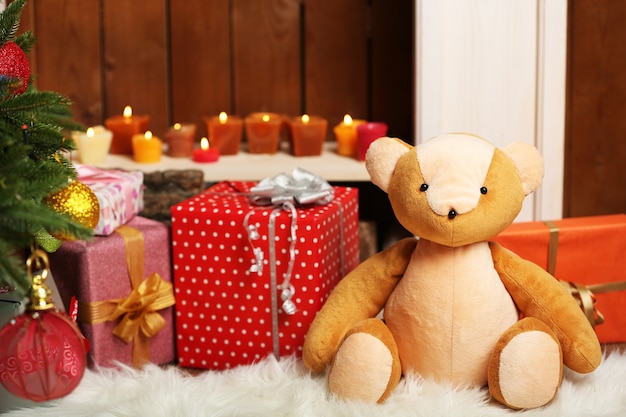 Teddy bear with Christmas gifts in room