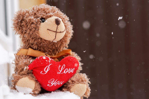 A teddy bear with a heart on the window. The concept of a Valentine's Day holiday, tender romantic