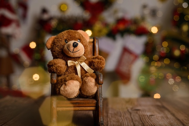 Teddy bear on wooden table with blurred Christmas background