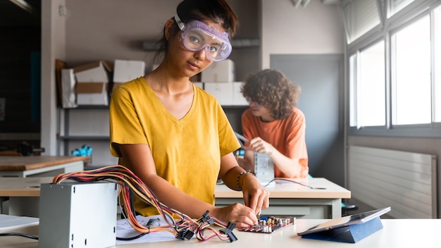 Teen asian girl high school student in class learning electronics looking at camera. Horizontal banner image. Copy space. Education concept.